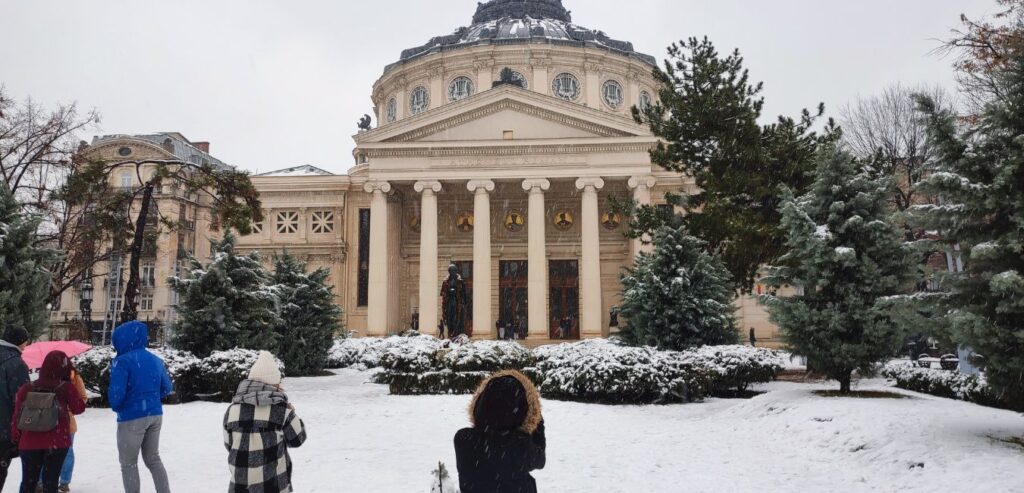 People taking picture during winter in front of the Romanian Athenaeum